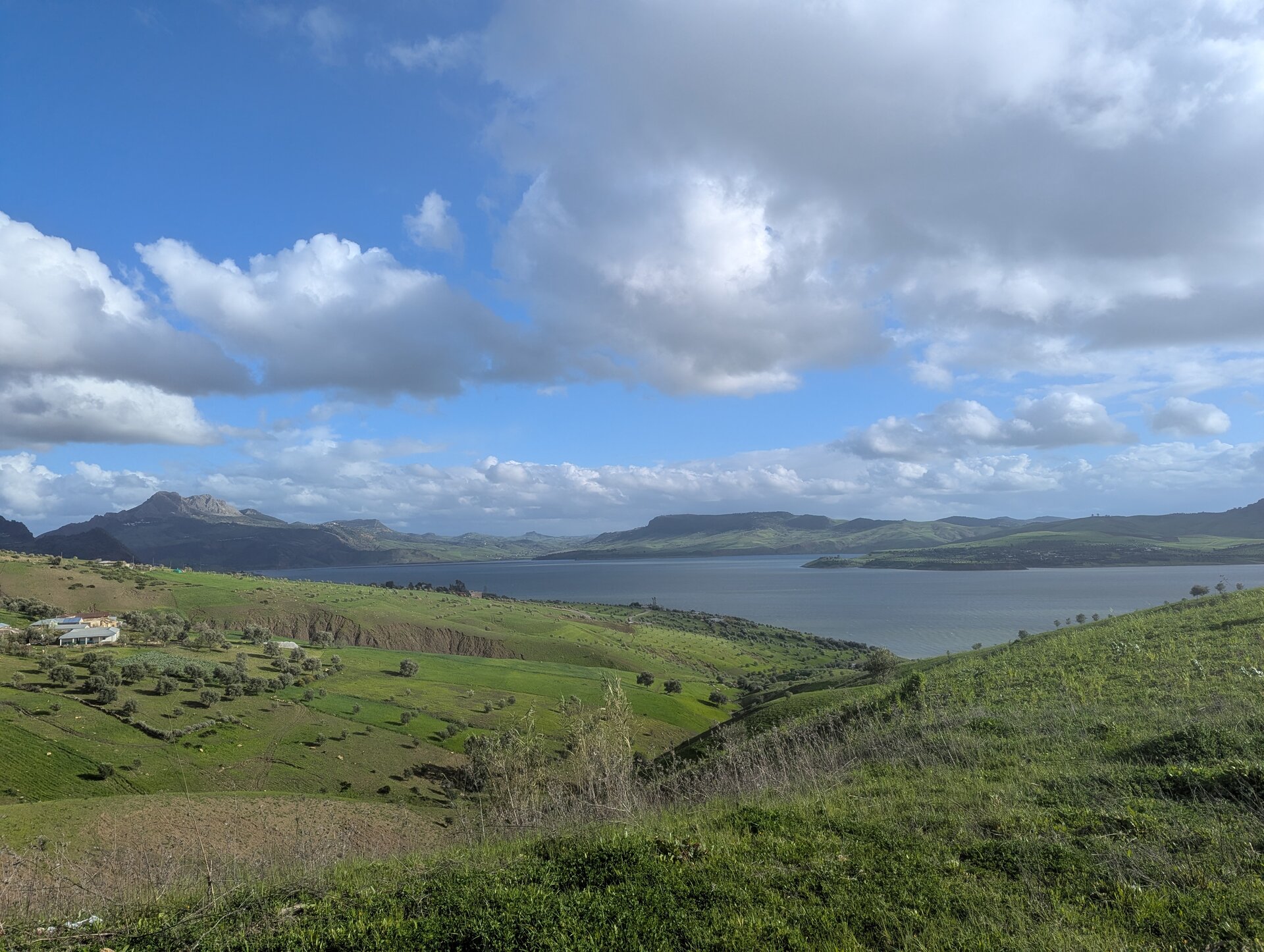 Green hillside sloping down to a large lake with mountains beyond